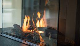 a fire burns in a glass fireplace, radiates heat