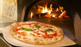 wyjmowanie pizzy z pieca opalanego drewnem